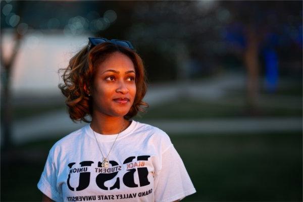 玛雅伍德森 stands outside on Grand Valley's campus in a "Black Student Union" Shirt.