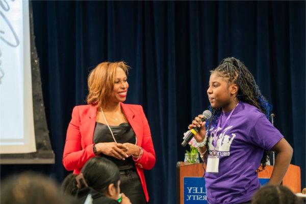 Erica Robertson stands next to a student as she answers a question into a microphone.